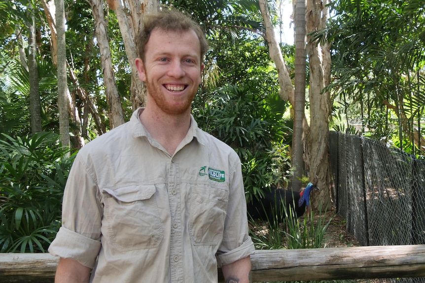 Smiling red haired man with cassowary in background