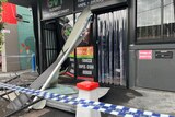 Twisted metal and broken glass lie outside a shop with a sign saying Glenroy Vape Tobacconist.