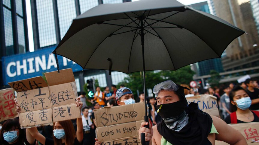Hong Kong protesters with signs and an umbrella