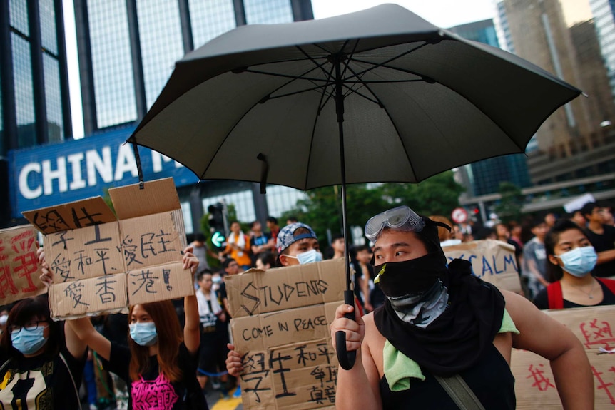 Hong Kong protesters with signs and an umbrella