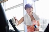 Woman cleans the handle of a cardio machine at the gym.