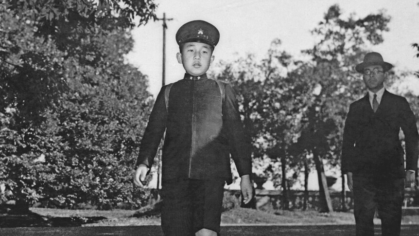 A black and white image of Emperor Akihito showing him walking in military uniform