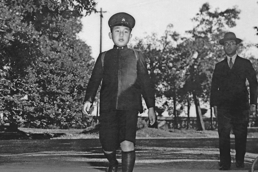 A black and white image of Emperor Akihito showing him walking in military uniform