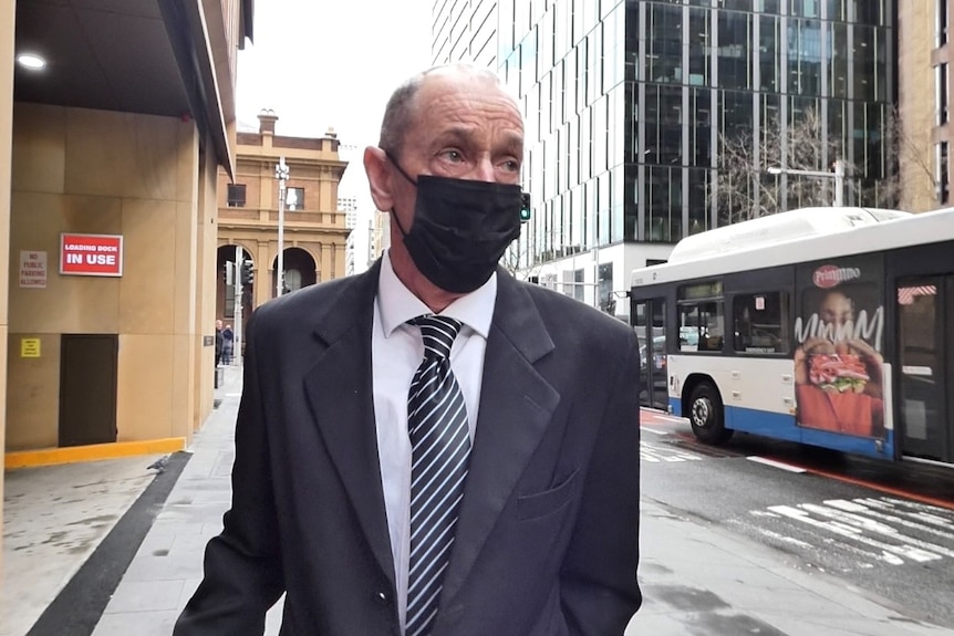 a man leaving court wearing a face mask