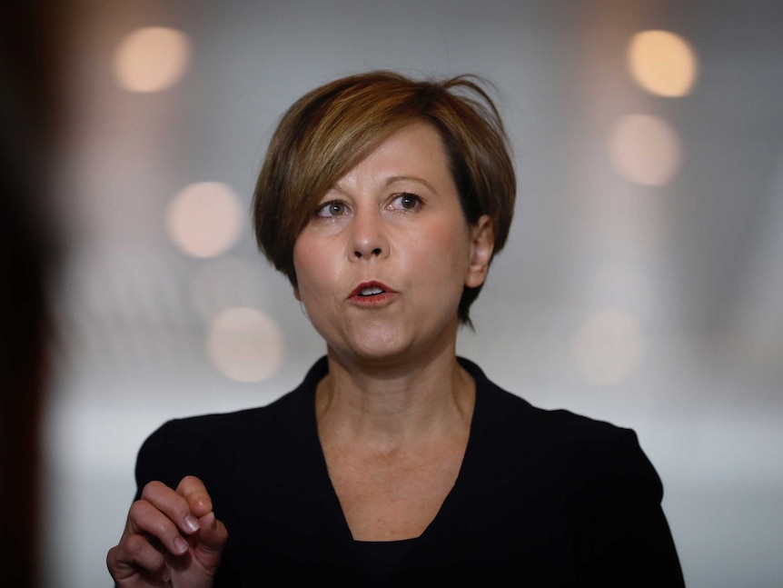 A woman with short, dark hair gestures as she speaks.