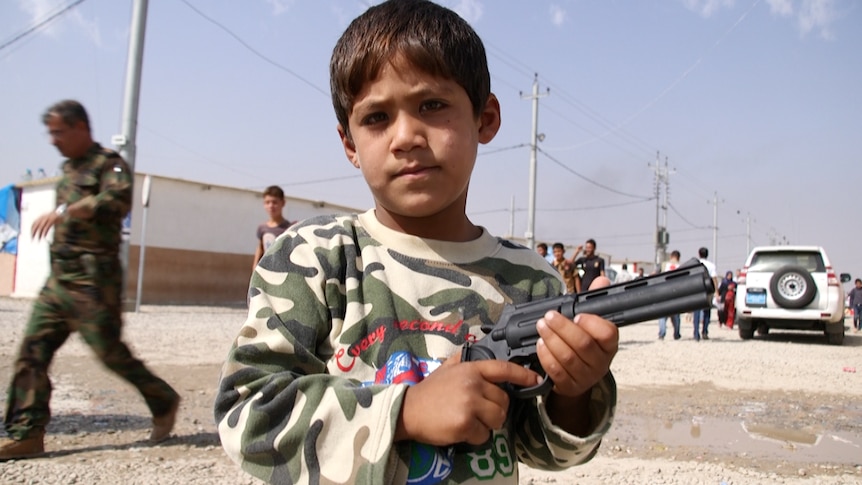 A little boy holds a gun in Debaga refugee camp.