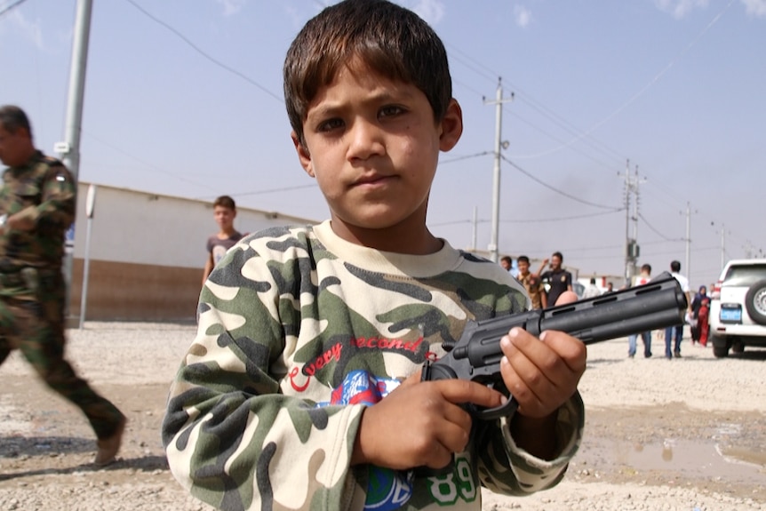 A little boy holds a gun in Debaga refugee camp.