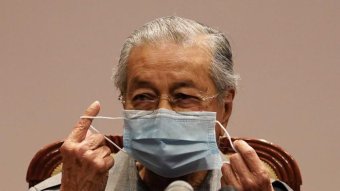 Mahathir Mohamad puts on a face mask.