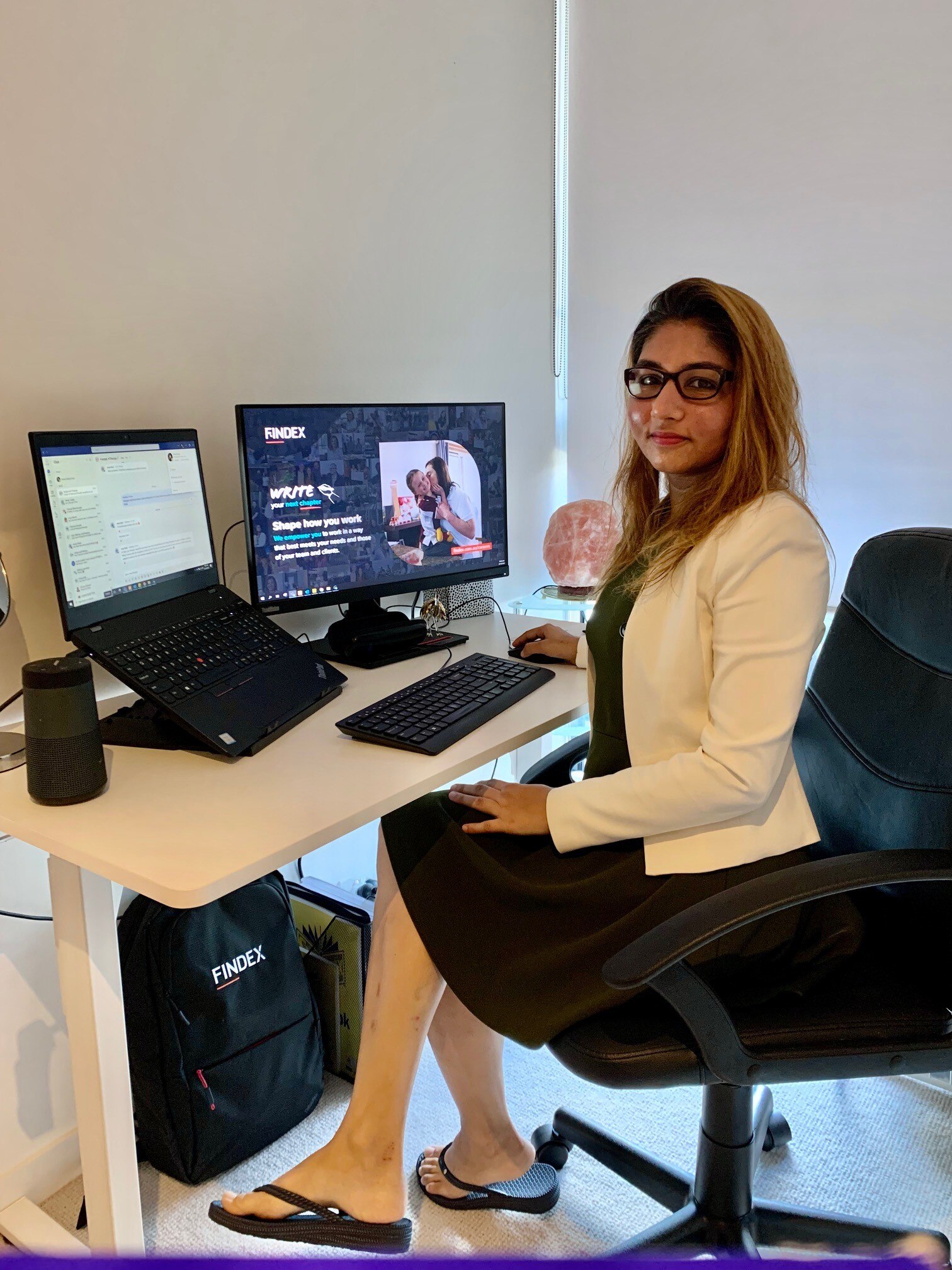 A woman in her mid to late thirties sits at her working from home office deak