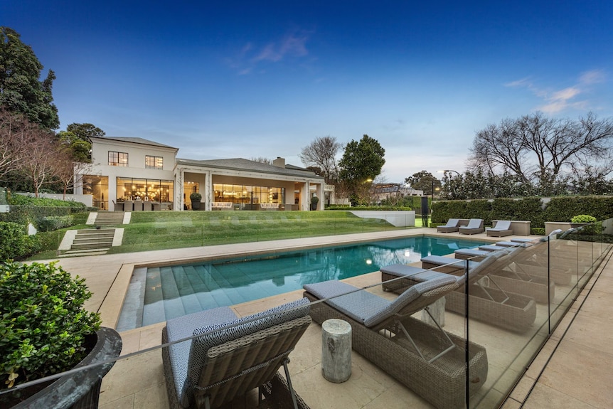 A swimming pool, lawn and mansion.