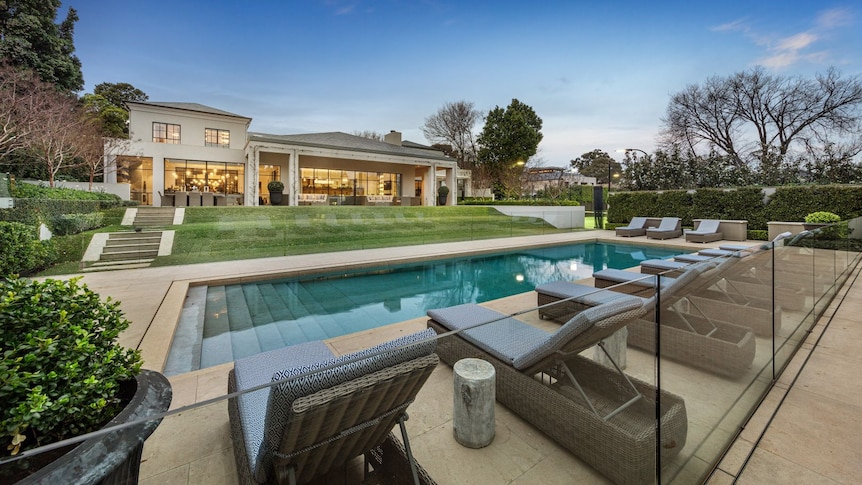 A swimming pool, lawn and mansion.