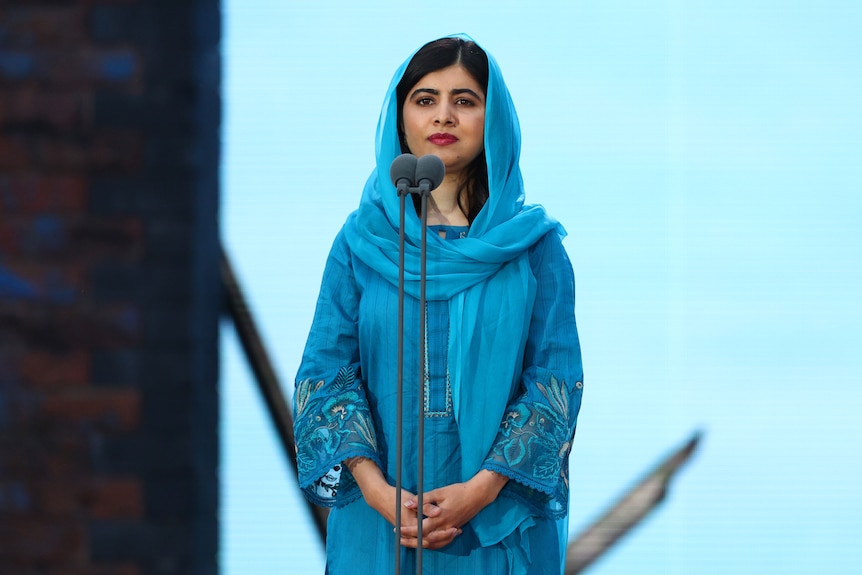 Malala Yousafzai stands with her hands clasped in front of her