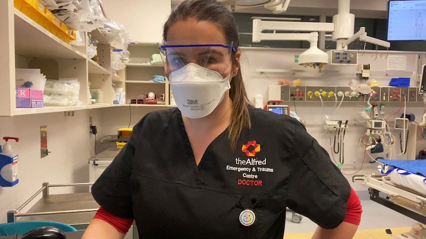 A doctor wearing a face mask and visor in a hospital.