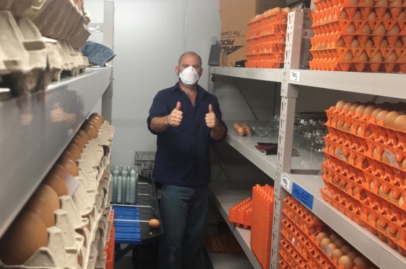 Paul Heaton giving the thumbs up while wearing a face mask next to eggs in his cold room.