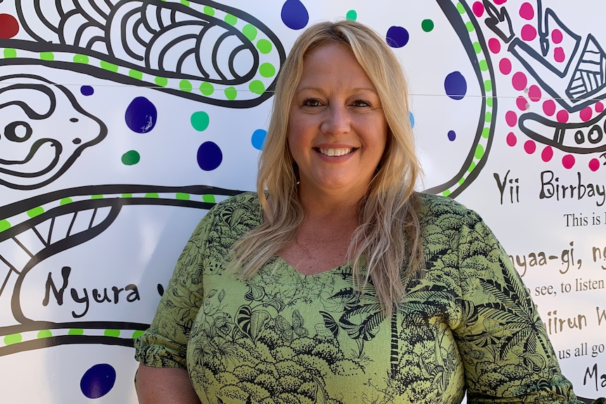 a woman standing in front of a wall mural