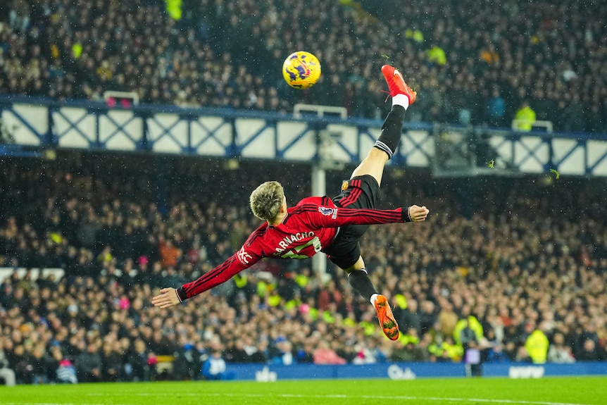 A Manchester United player connects with the ball in mid-air with his back to goal.
