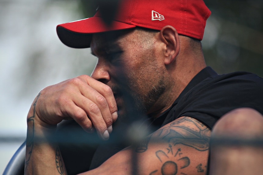 Man with his hand to his face, with a thoughful expression. 