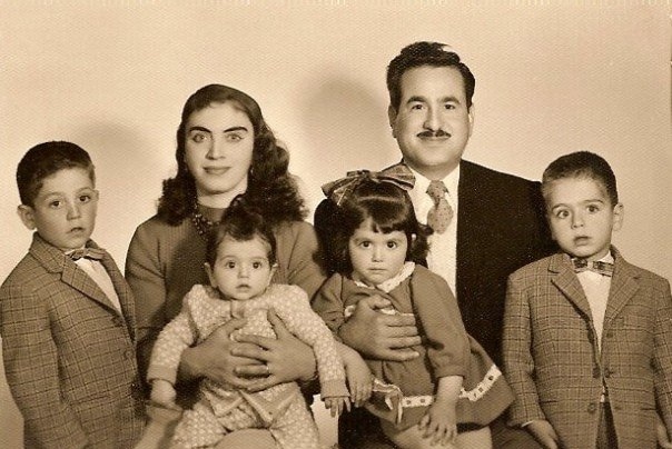 A black and white family photo of a couple with their four young children.