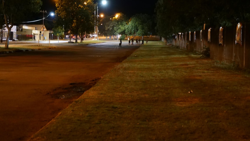 a road at night and in the distance unidentifiable children