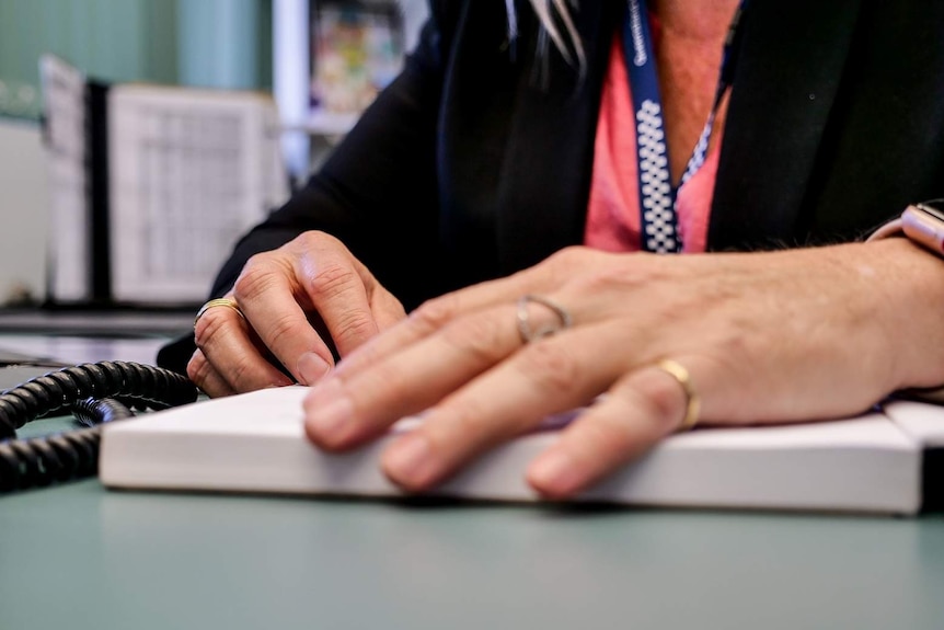 A photo focused on a woman's hands. The front hand is out of focus, but rings are worn. The read hand is focused, with a ring.