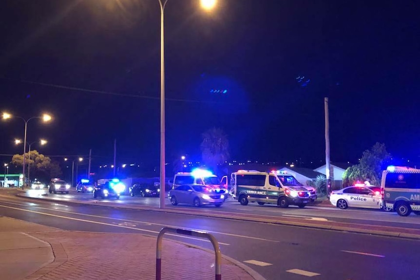 Ambulances and police cars outside a house at night.