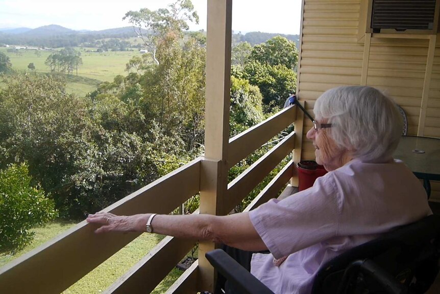 Woman in wheelchair overlooking back garden and surrounding hills.