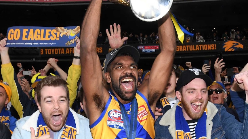 west coast eagles player Liam Ryan holds AFL premiership cup above his head at stadium