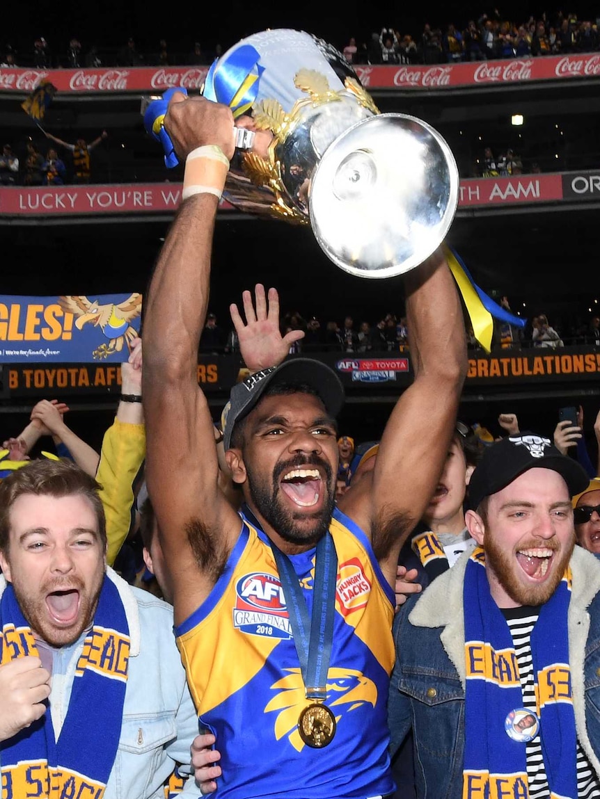 west coast eagles player Liam Ryan holds AFL premiership cup above his head at stadium