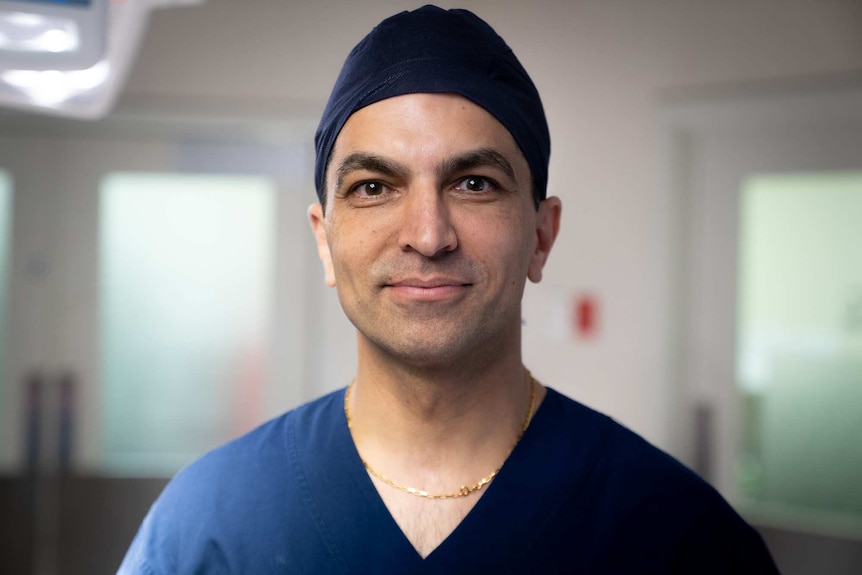 A tight portrait of a surgeon smiling in a surgeon's cap