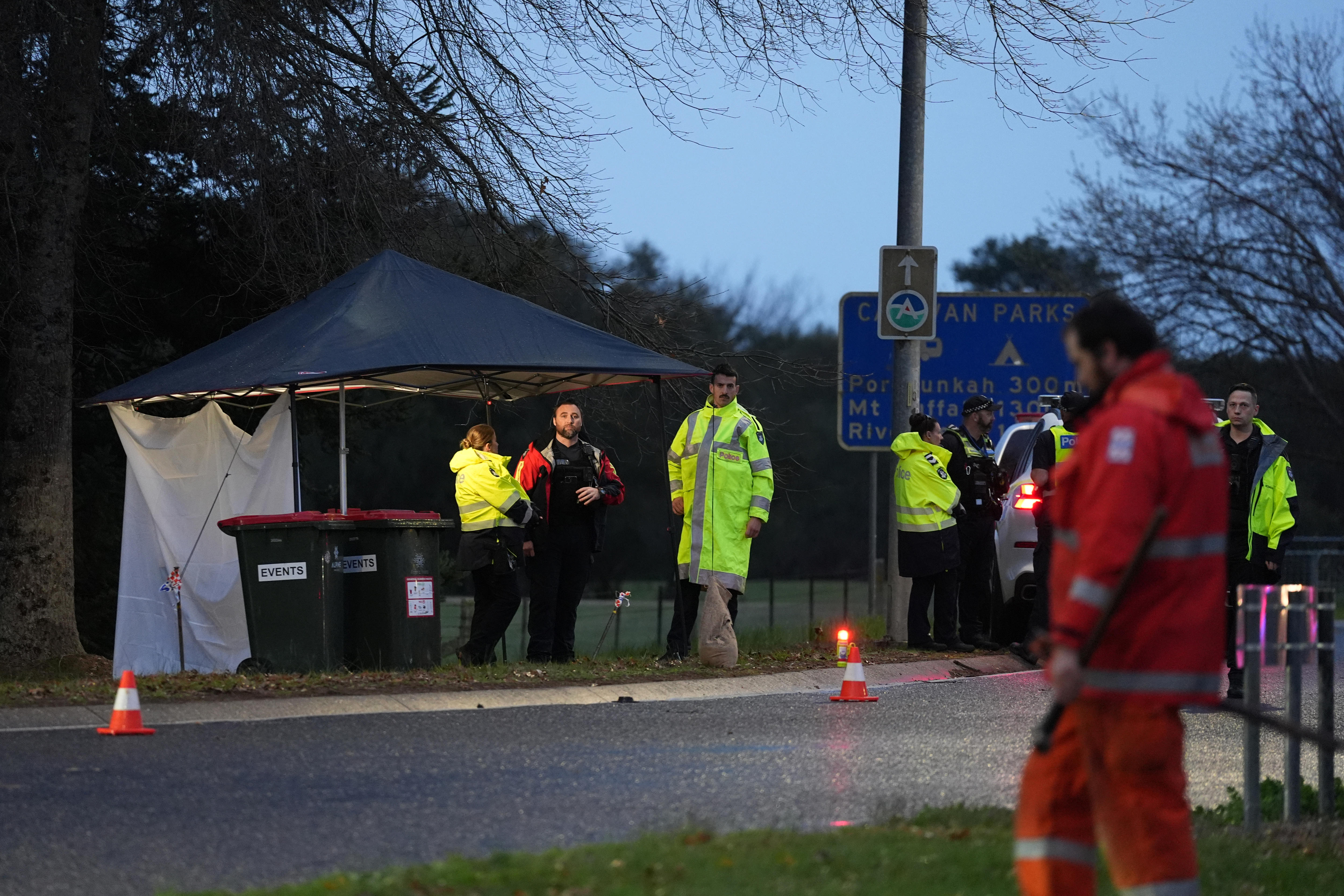 Multiple officers dressed in hi-vis standing on a road at night time under a tent as the manhunt continues