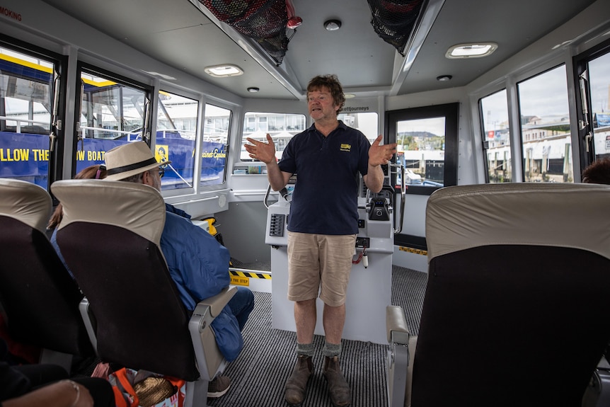 a man in a boat addressing tourists