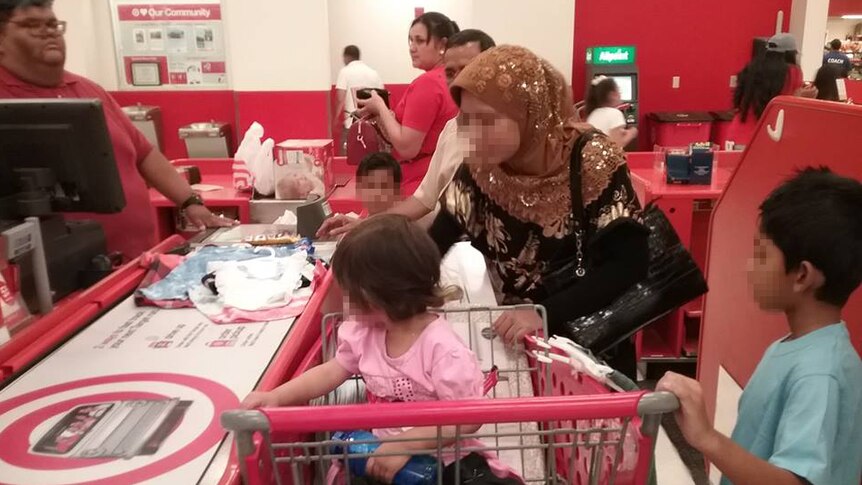 A woman with her children at the checkout, purchasing children's clothing  in the US.
