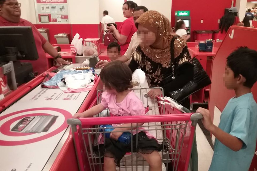 A woman with her children at the checkout, purchasing children's clothing  in the US.