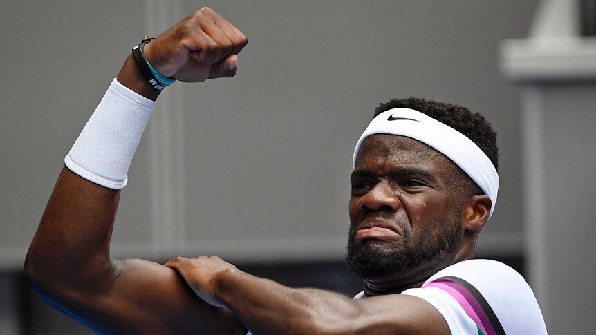 Frances Tiafoe flexes his right biceps muscle as he celebrates a win at the Australian Open.