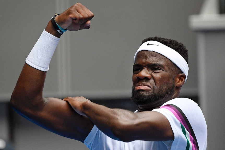 Frances Tiafoe flexes his right biceps muscle as he celebrates a win at the Australian Open.