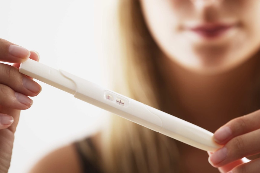 A woman holding a pregnancy test.