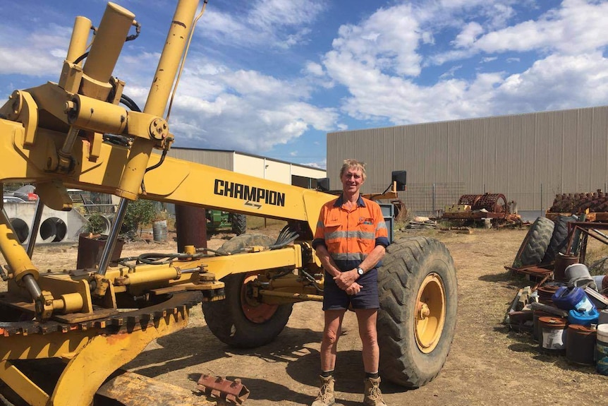 Stuart Redman standing in front of earth moving tractor in Gloucester.
