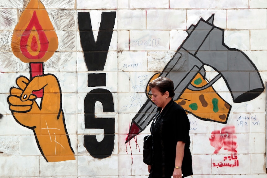 Egyptian walks past election graffiti