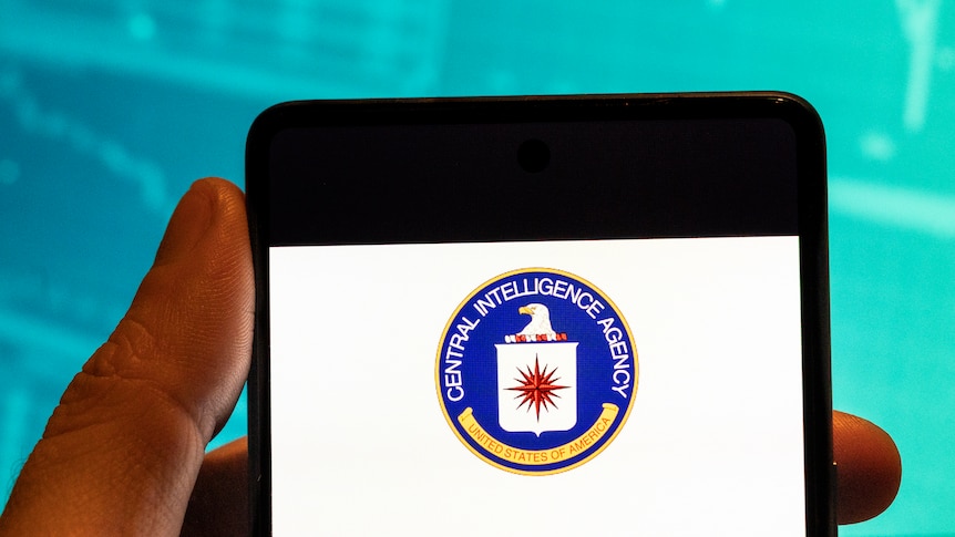 hand holds phone with image of CIA logo on it 