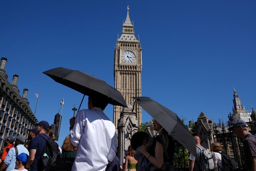 People walk past Big Ben in London on a bright, sunny day.