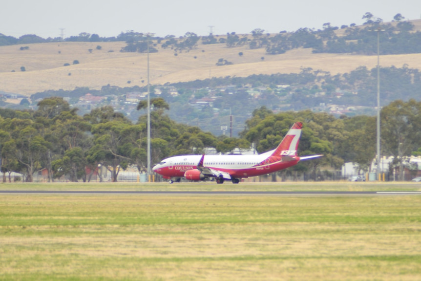 A red and white, large plane landing on the tarmac