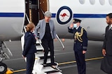 Penny Wong disembarks from a plane onto the tarmac while a man in uniform salutes.