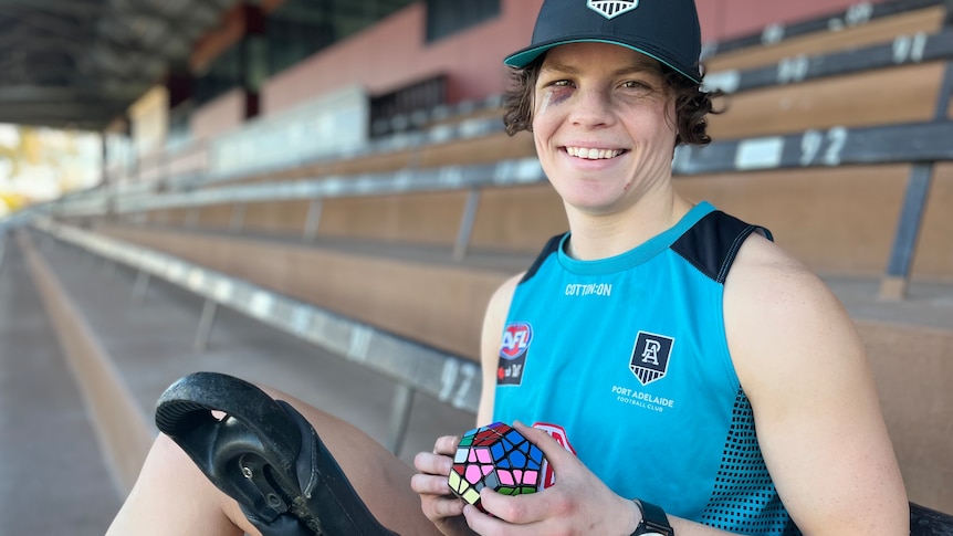 Close-up of Ebony O'Dea smiling with a Rubik's cube and her unicycle in the Port Adelaide grandstand