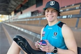 Close-up of Ebony O'Dea smiling with a Rubik's cube and her unicycle in the Port Adelaide grandstand