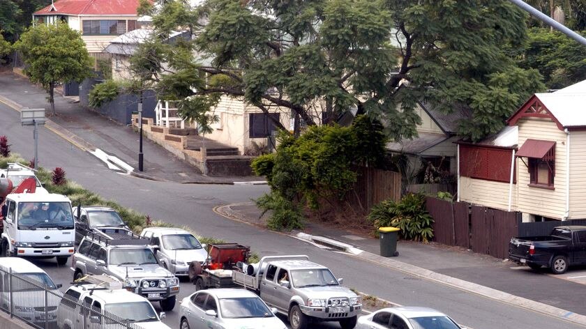 Peak hour traffic passes close by residential houses on Hale Street