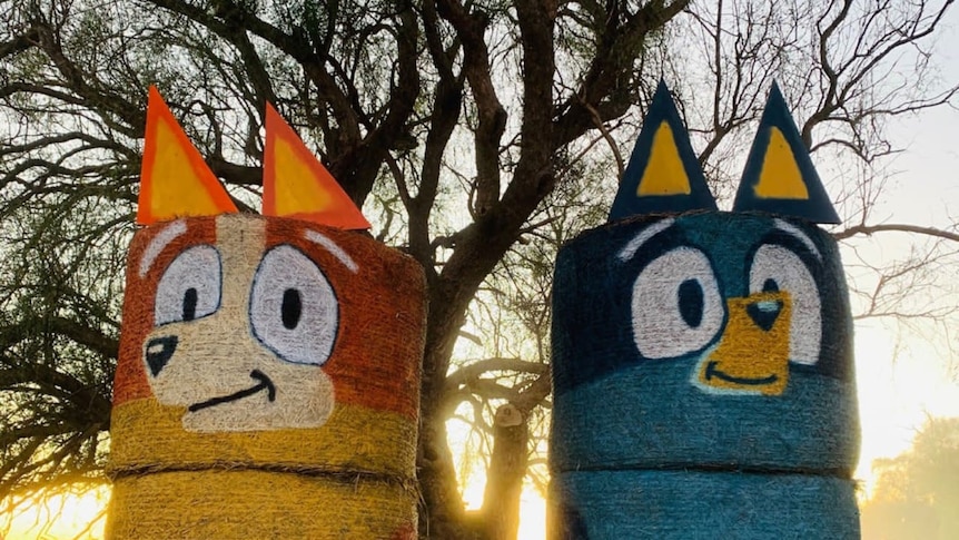 Two bales of hay painted to look like Bluey and Dingo.