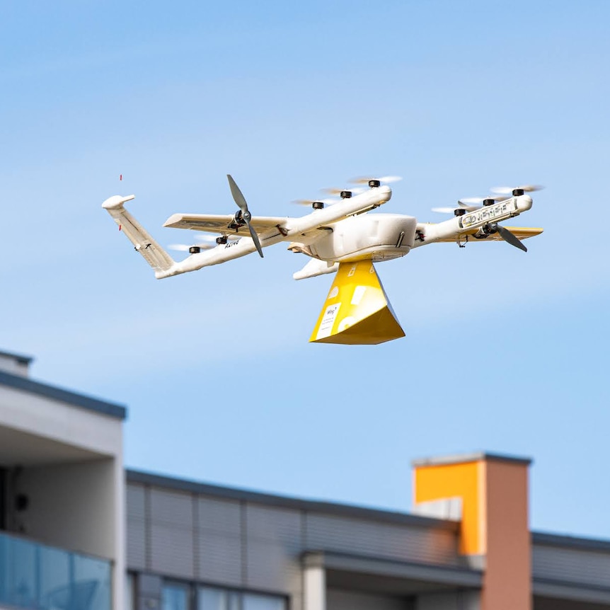 An airborne drone carrying a parcel.