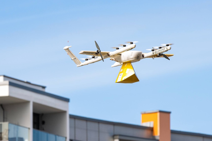 An airborne drone carrying a parcel.