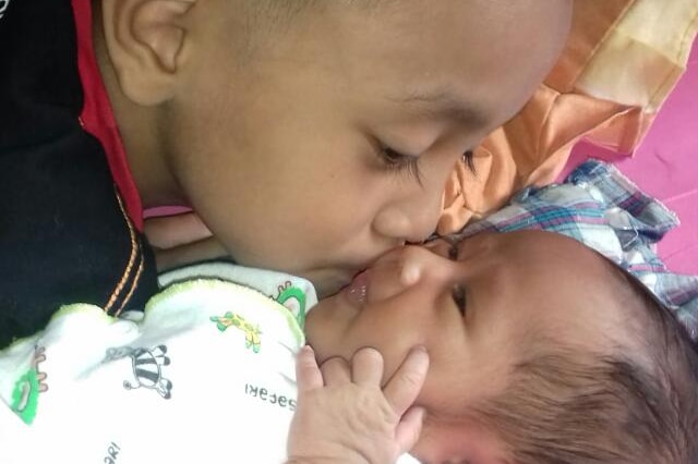 Virgenio kisses baby Alexa on the cheek.