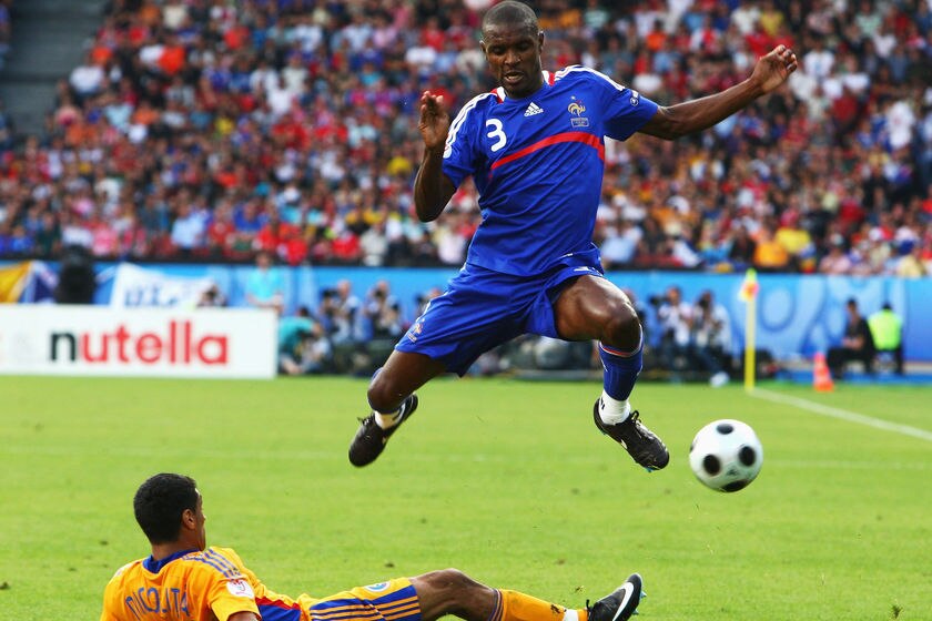 Eric Abidal leaps over a tackle by Banel Nicolita